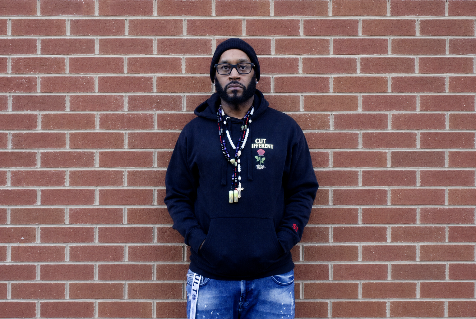 2Dollarsigns, hip-hop recording artist Jaime Fenderson, standing against a brick wall